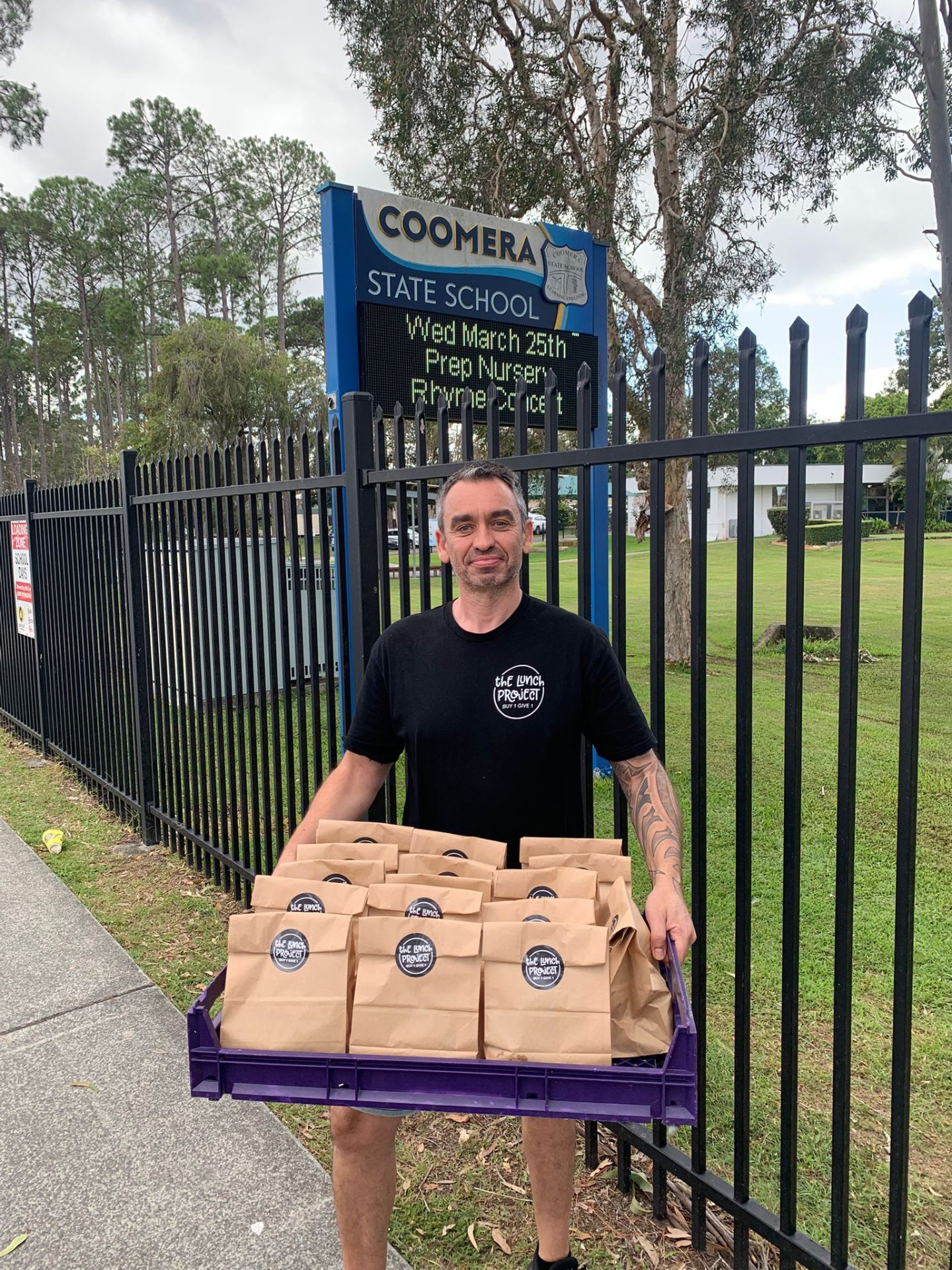 Lunch Project volunteer delivering a crate of lunches to the gates of Coomera State School
